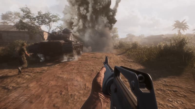 A US tank and soldier moving through a smoky jungle road